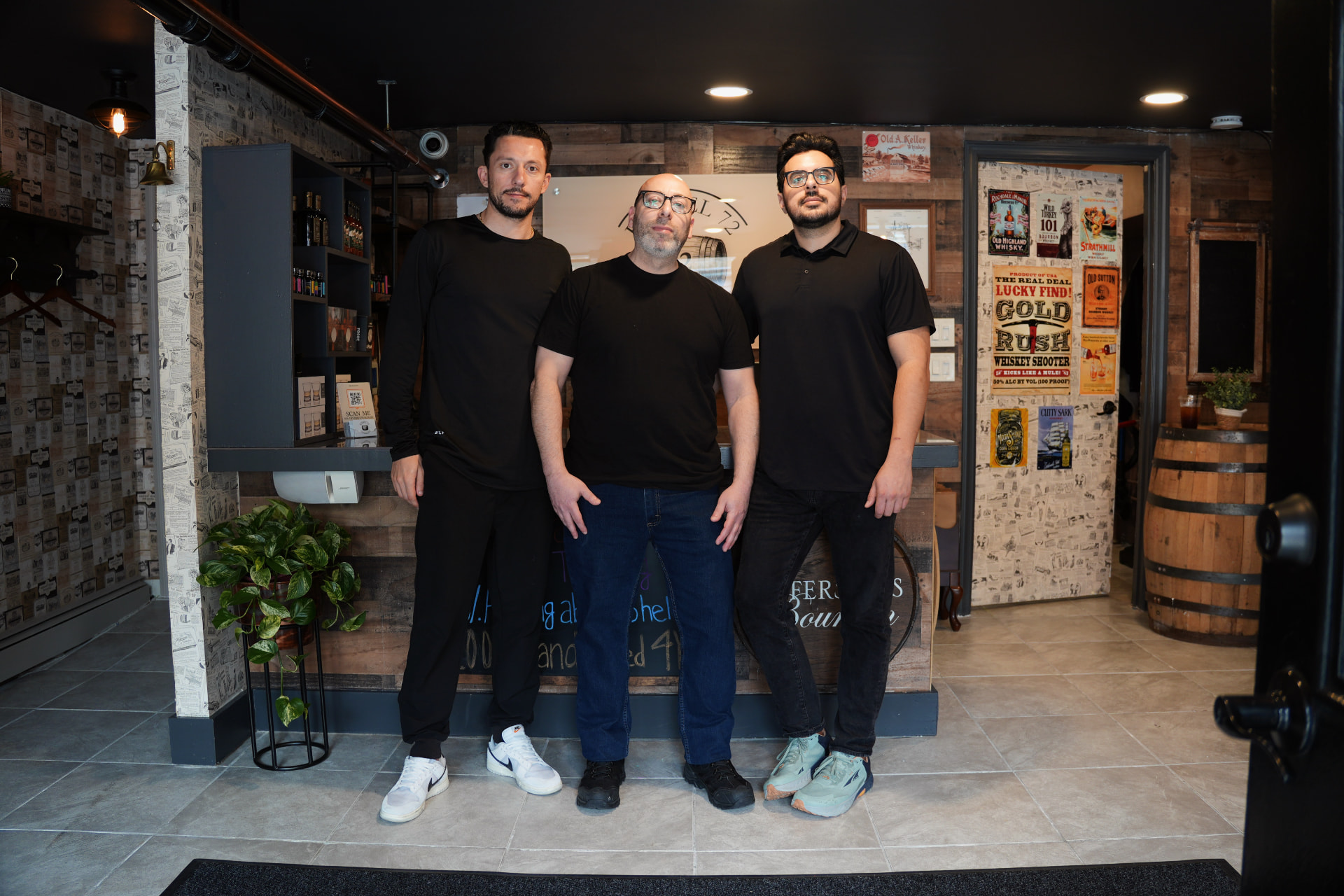Three Barrel 72 team members in black shirts standing together in front of the shop counter